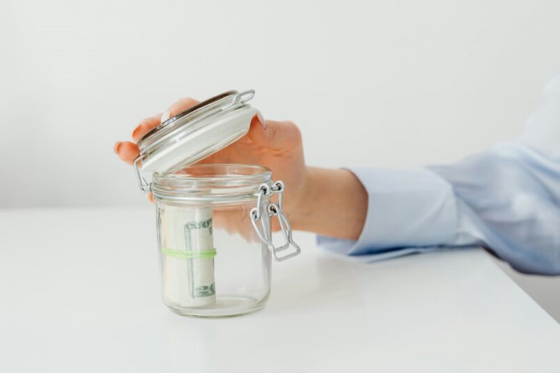 Person writing down financial goals like 'Retirement' or 'House Down Payment'