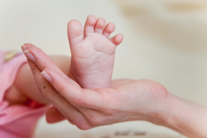 Healthcare provider gently interacting with a pregnant person or young infant